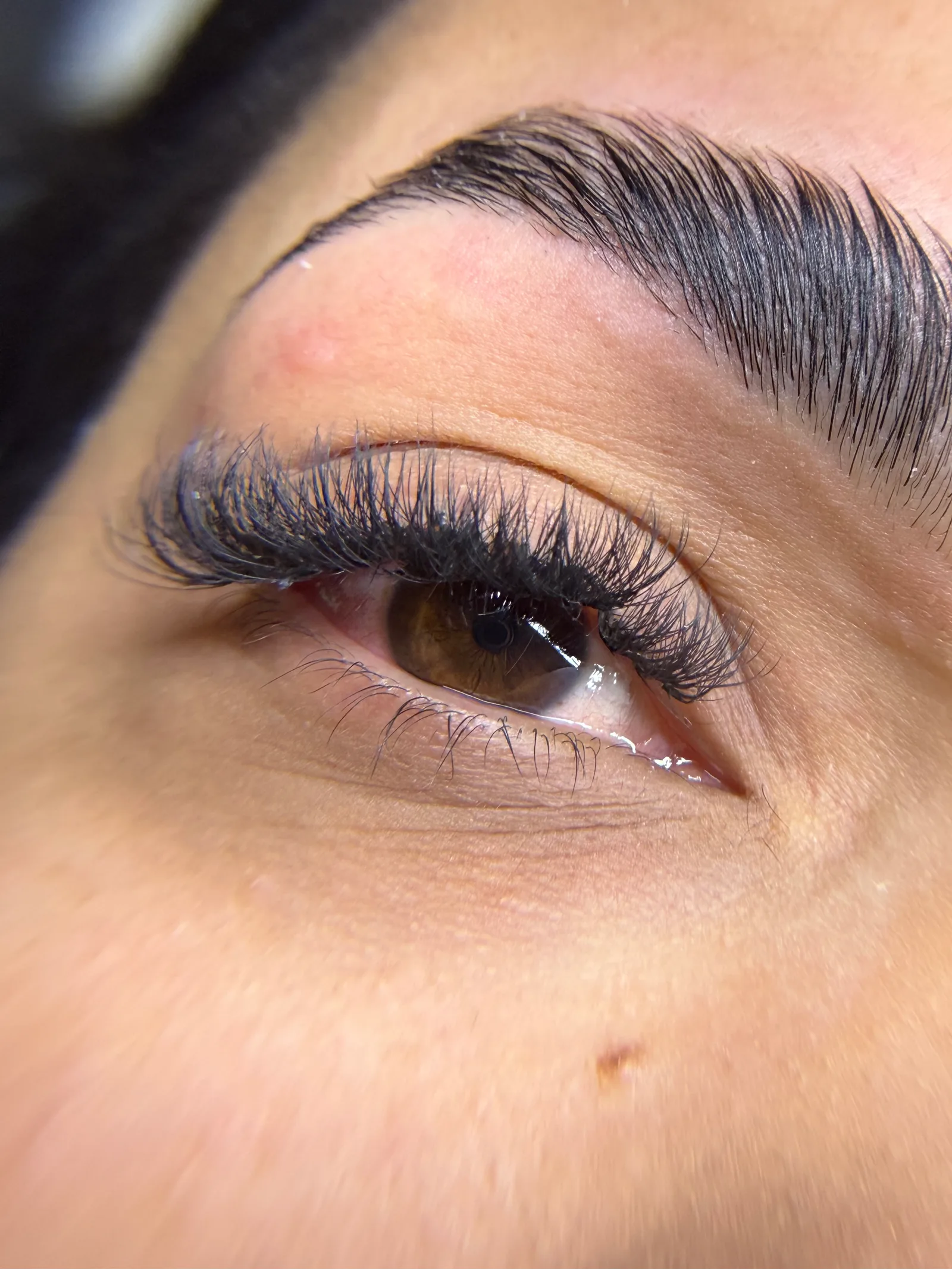 Close de um olho com extensão de cílios volumosos e sobrancelha desenhada