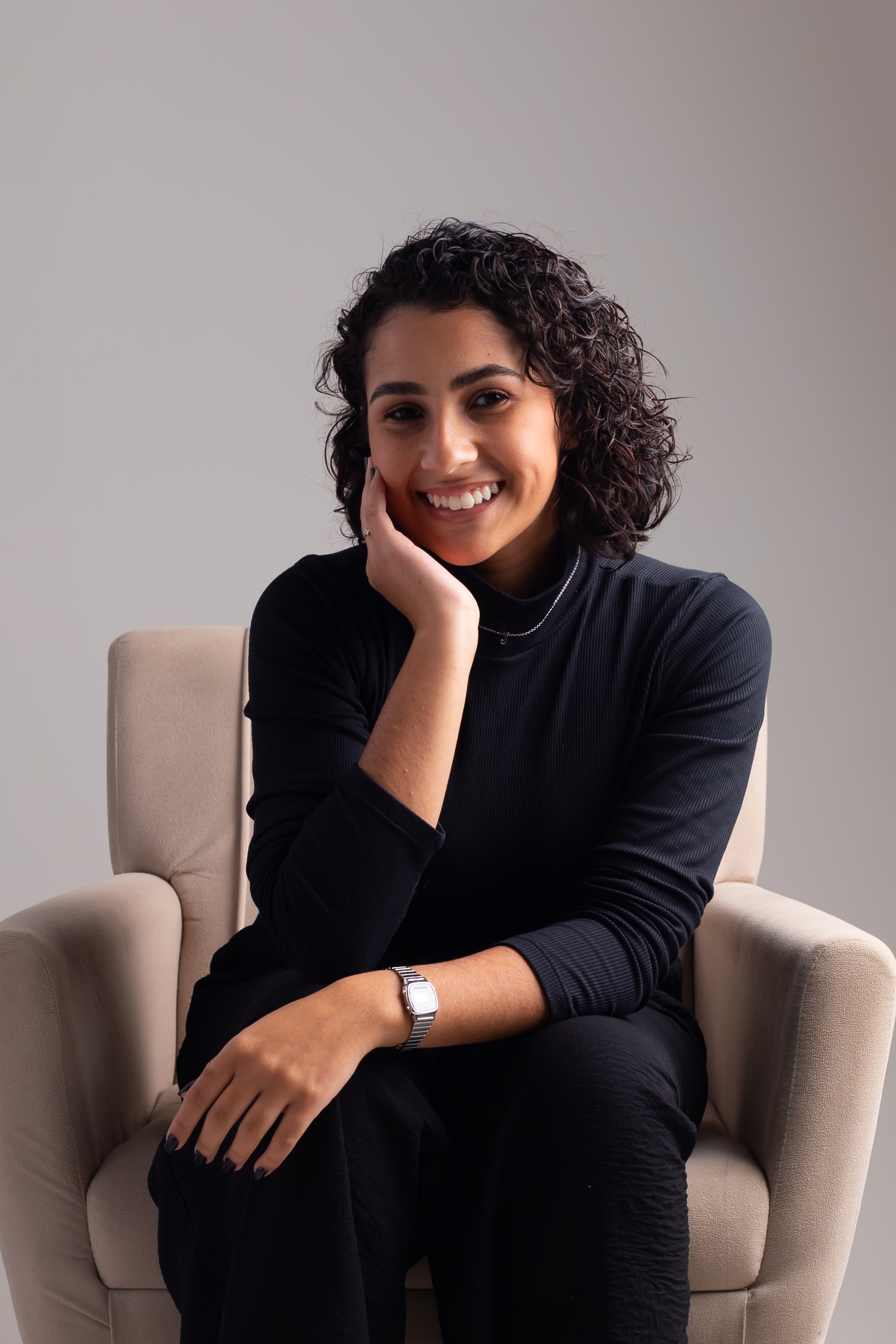 Sol, profissional do JS Studio, sorrindo sentada em uma poltrona